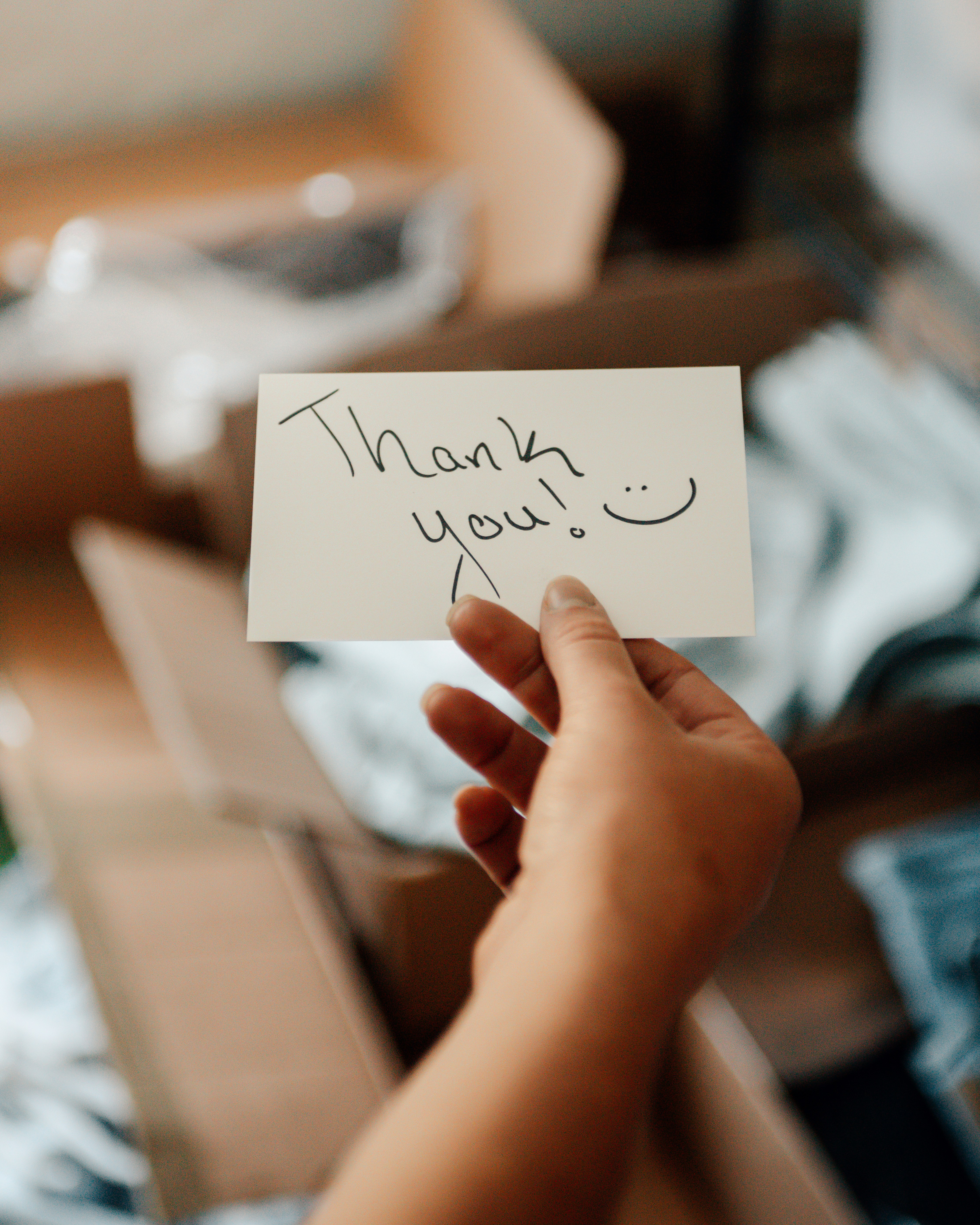 Hand holding a thank you note with a smiley face